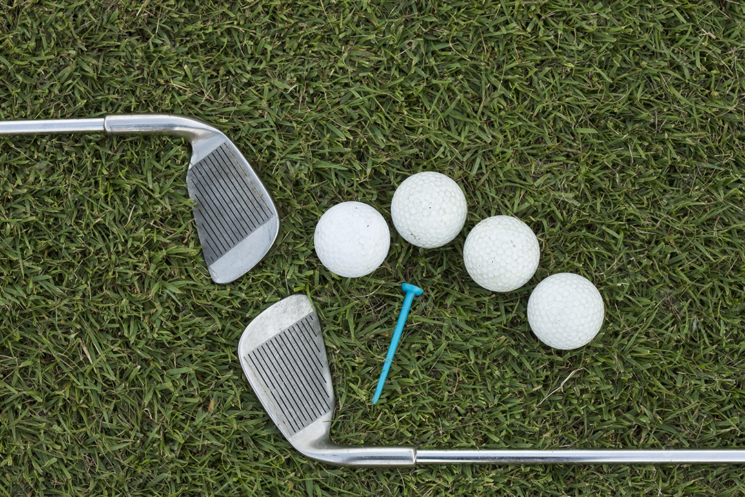 Clube de golfe e bola na grama