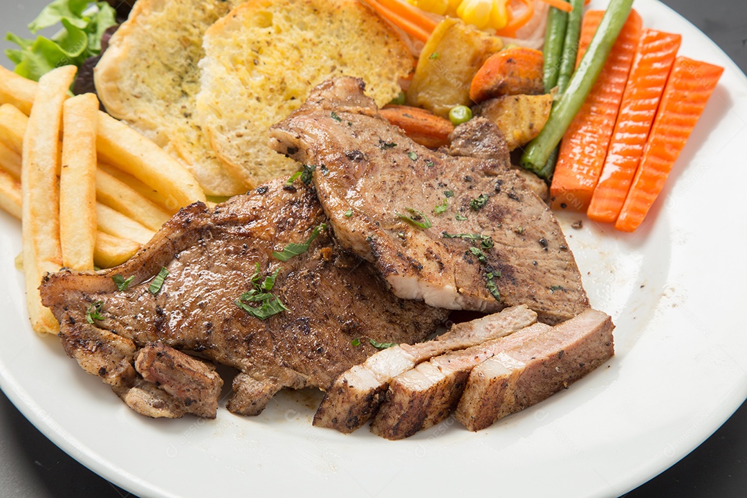 Bife de carne e salada de legumes em um prato.