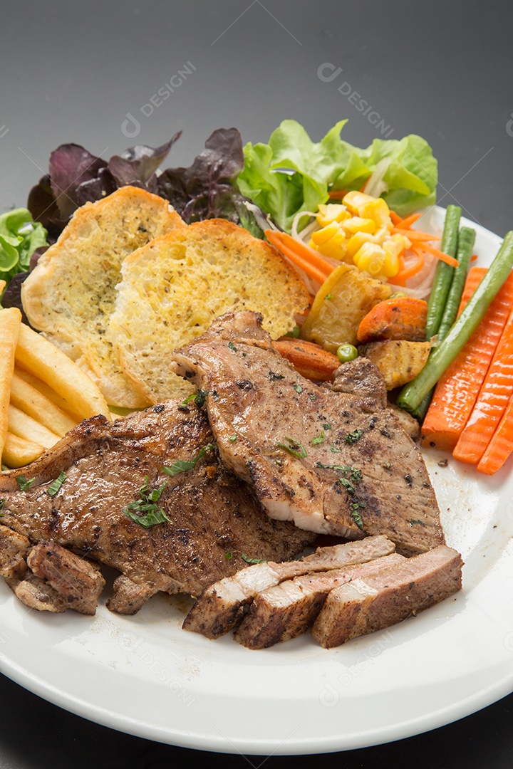 Bife de carne e salada de legumes em um prato.