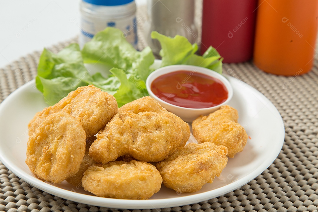 Pilha de nuggets de frango na chapa branca com molho