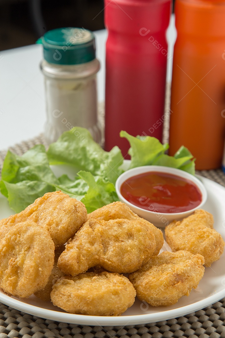 Pilha de nuggets de frango na chapa branca com molho