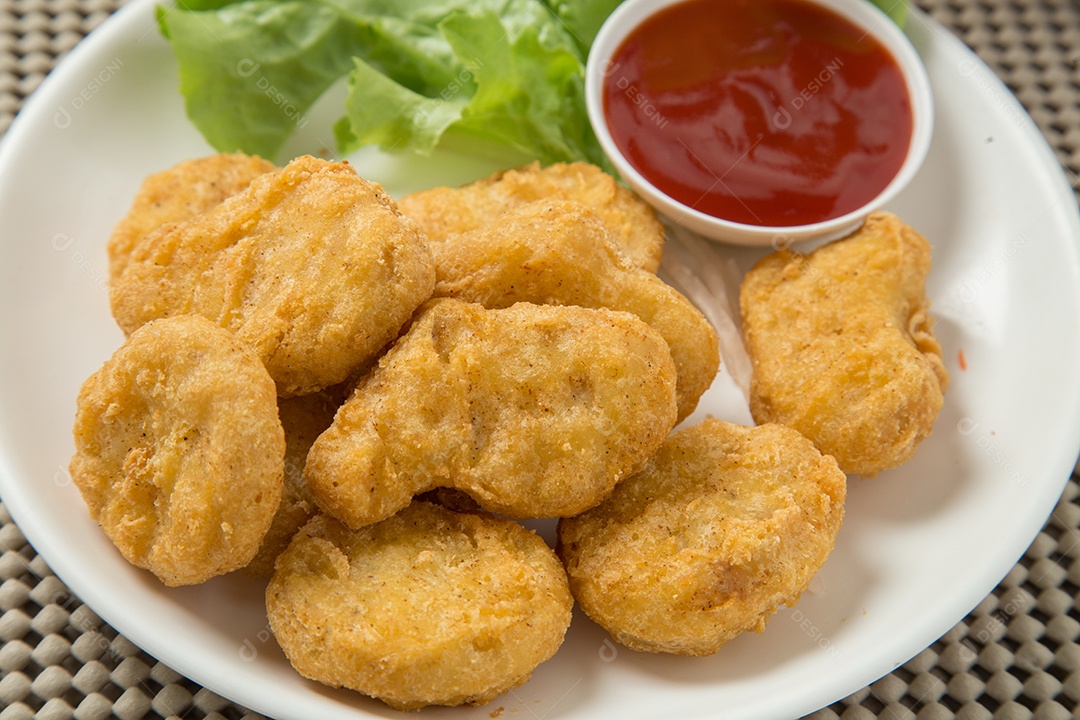 Pilha de nuggets de frango na chapa branca com molho
