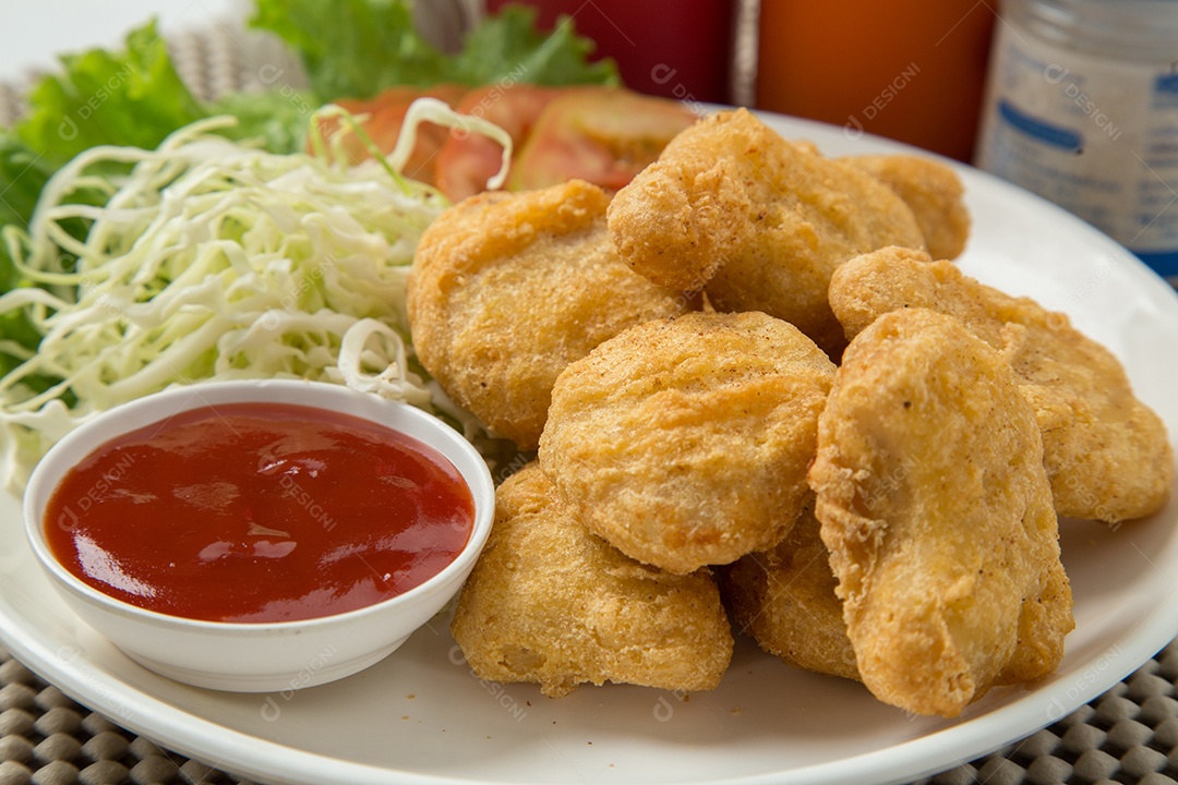 Pilha de nuggets de frango na chapa branca com molho