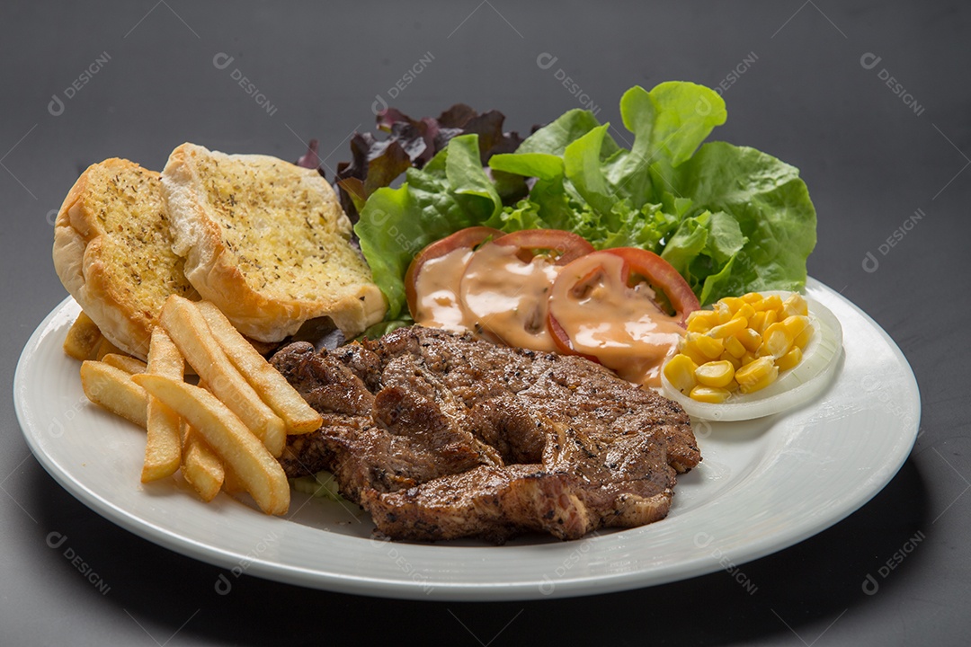 Prato branco de comida bife batata fritas com salada sobre uma mesa de restaurante
