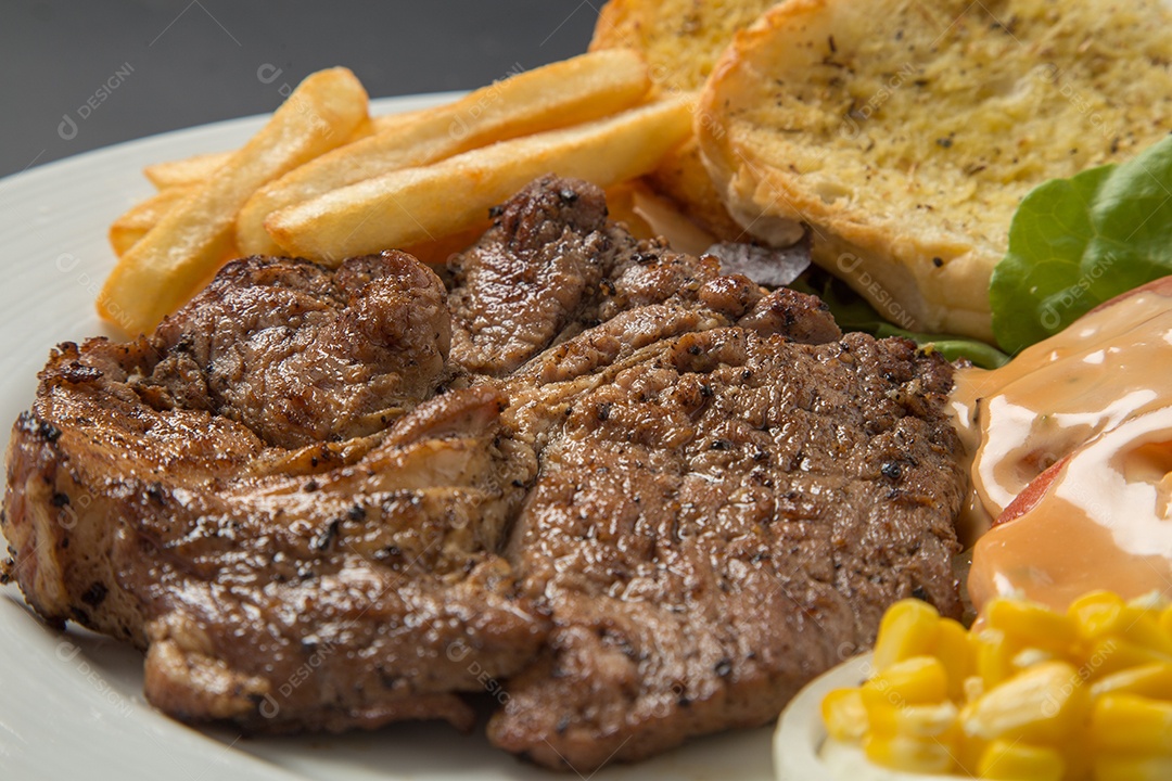 Prato branco de comida bife batata fritas com salada sobre uma mesa de restaurante