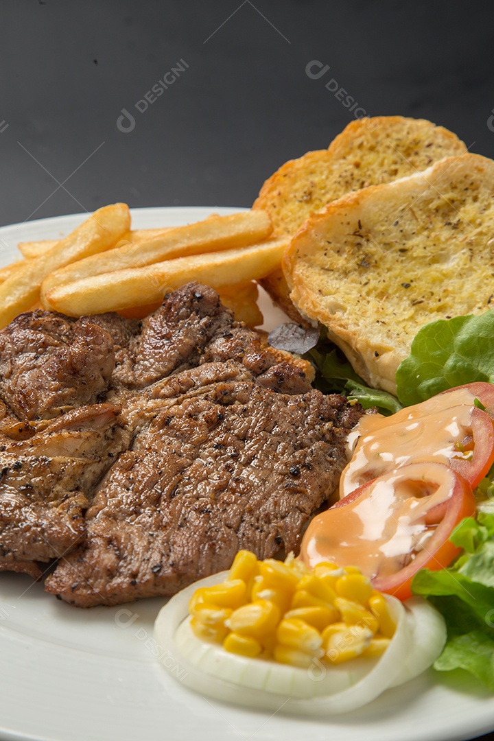Prato branco de comida bife batata fritas com salada sobre uma mesa de restaurante