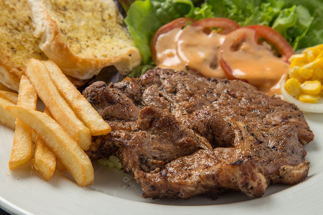 Prato branco de comida bife batata fritas com salada sobre uma mesa de restaurante