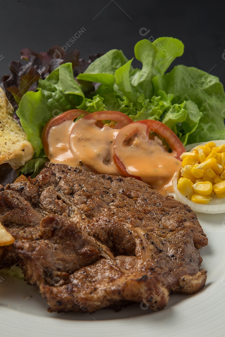 Prato branco de comida bife batata fritas com salada sobre uma mesa de restaurante