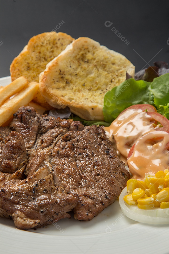 Prato branco de comida bife batata fritas com salada sobre uma mesa de restaurante