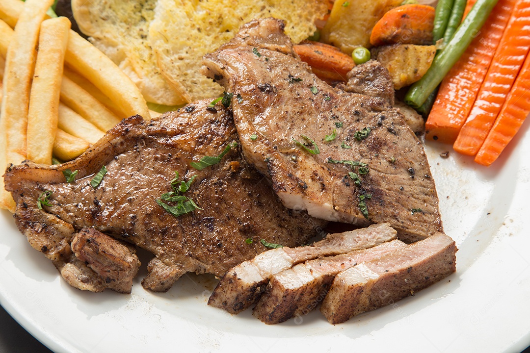 Bife de carne e salada de legumes em um prato.