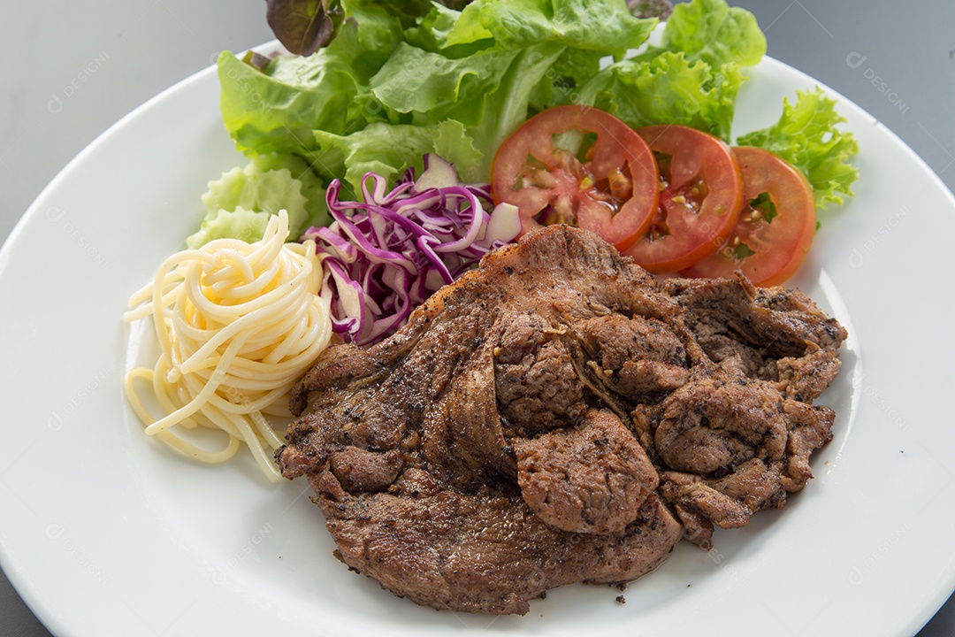 Bife de carne e salada de legumes em um prato.