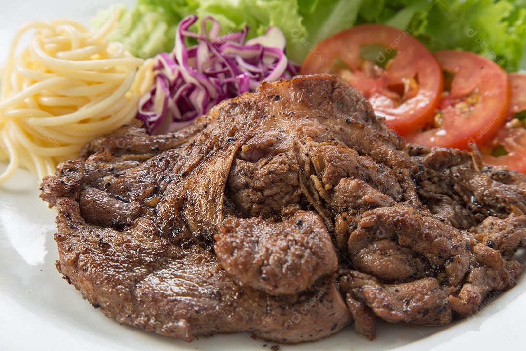 Bife de carne e salada de legumes em um prato.