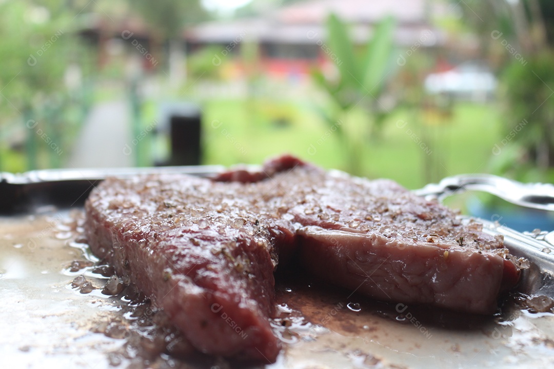 Carne sendo temperada para assar sobre uma tabua de madeira.