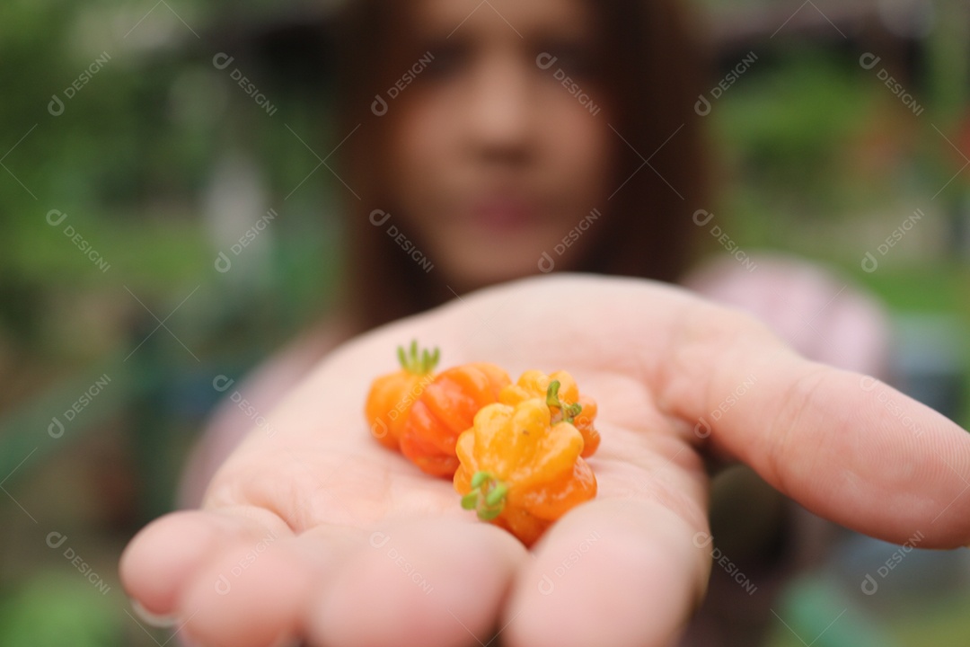 Mulher desfocada, segurando algumas pitangas na mão