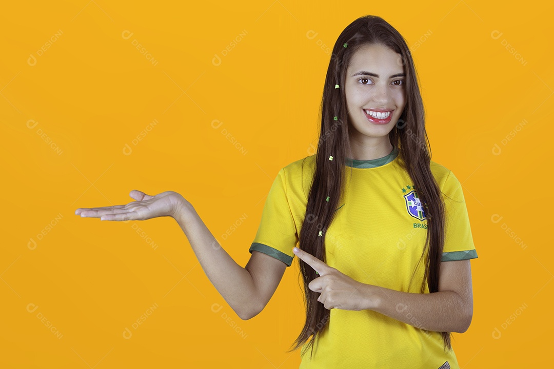 Linda mulher torcedora brasileira apontando para lado sobre fundo isolado amarelo