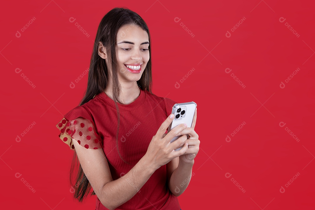Linda mulher jovem mexendo em seu celular smartphone sobre fundo vermelho