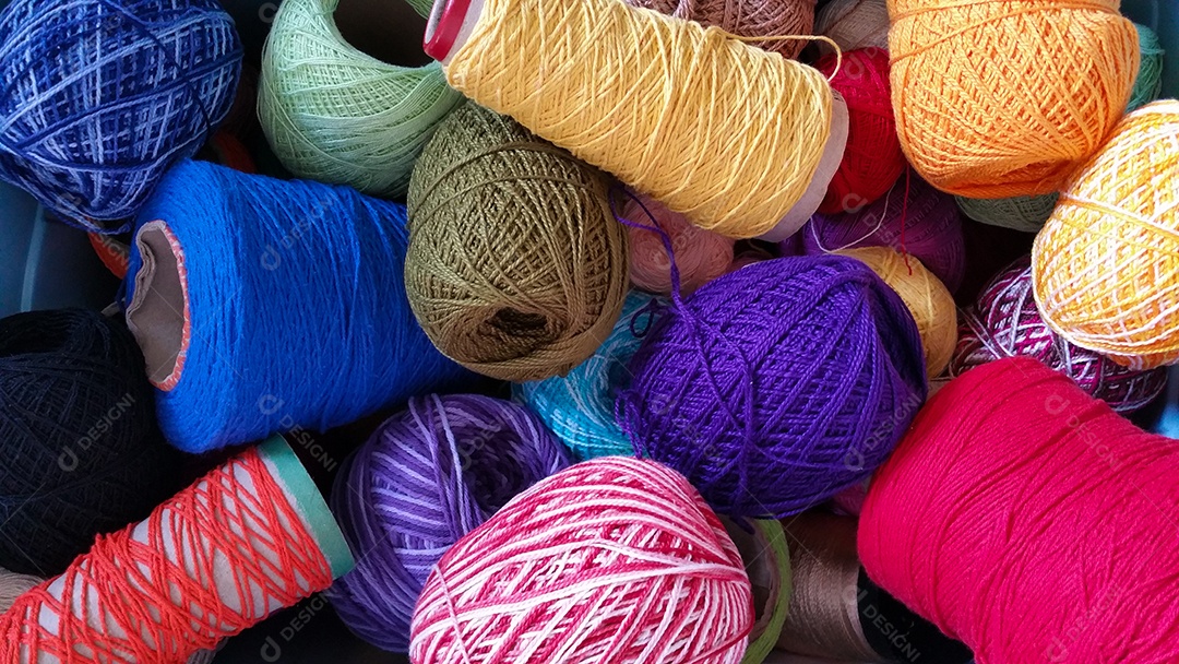 Vários rolos de fios de crochê coloridos empilhados.