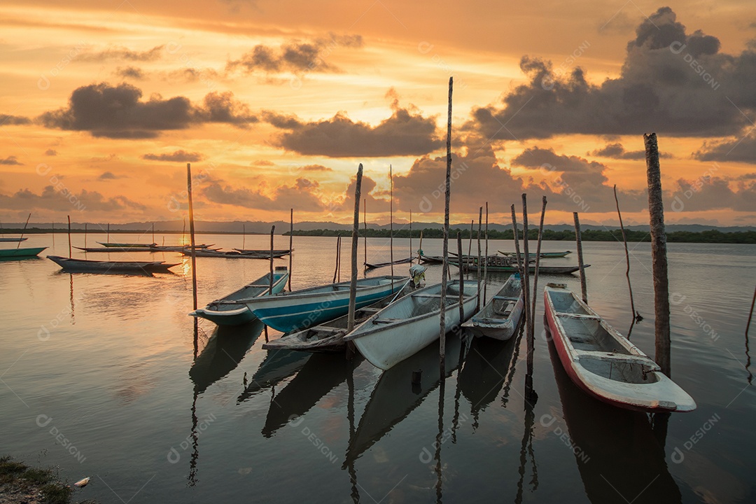 Paisagem com pôr do sol com canoas de pesca na beira do rio.