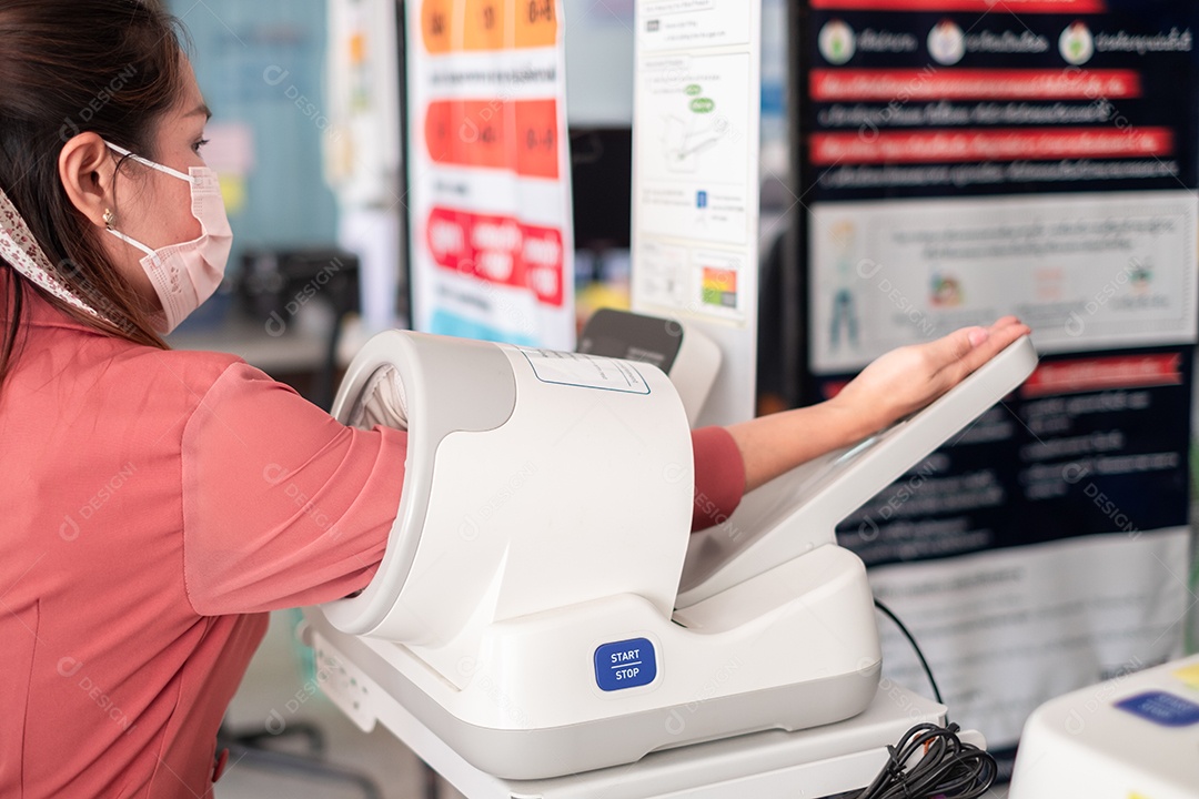 Pessoa asiática usando máquina automática de pressão arterial no hospital