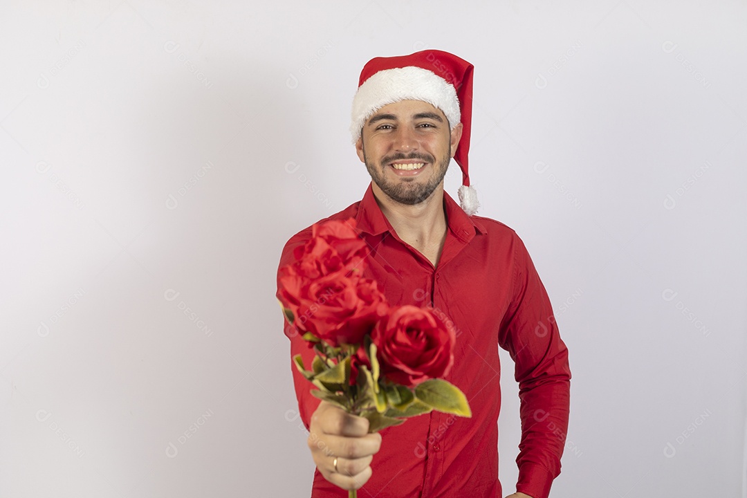 Homem jovem usando gorro Papai Noel segurando buquê flores sobre fundo branco