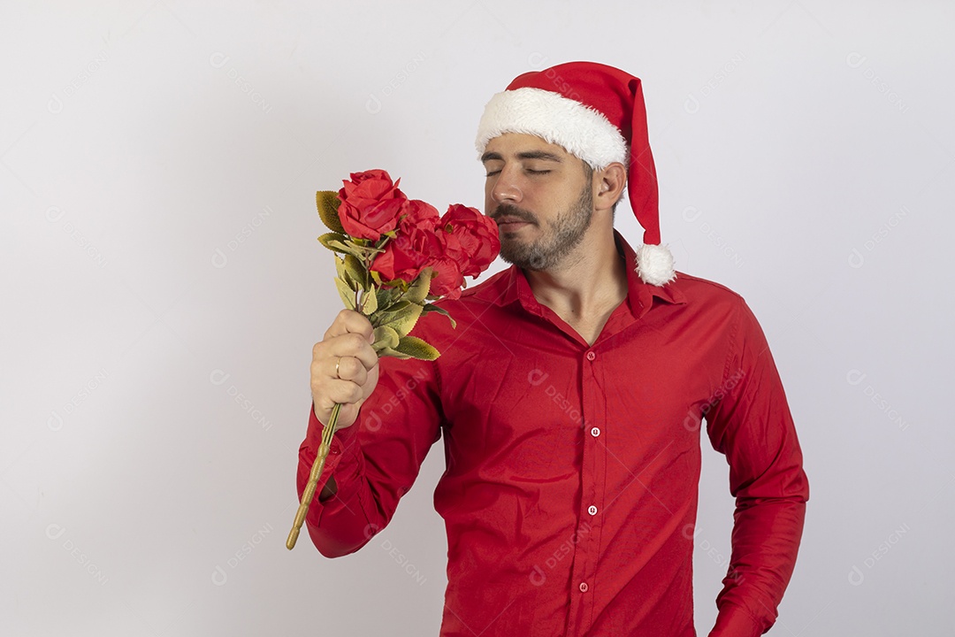 Homem jovem usando gorro Papai Noel segurando buquê flores sobre fundo branco