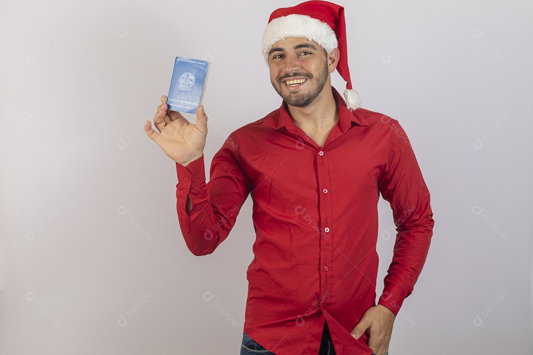 Homem jovem usando gorro Papai Noel segurando carteira de trabalho sobre fundo branco