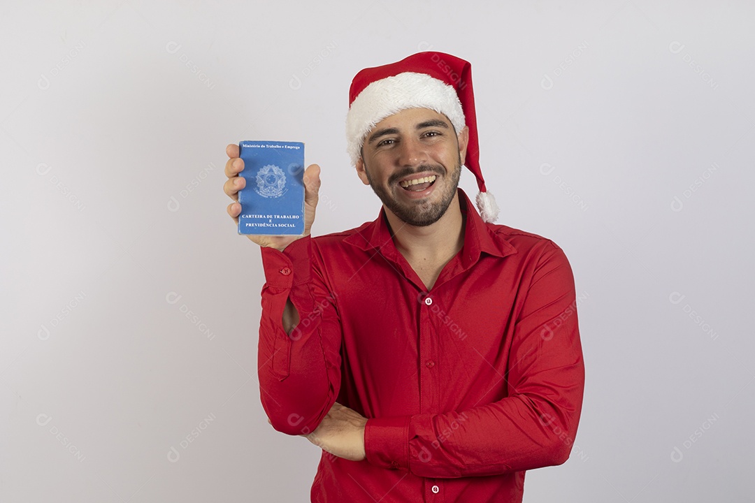 Homem jovem usando gorro Papai Noel segurando carteira de trabalho sobre fundo branco