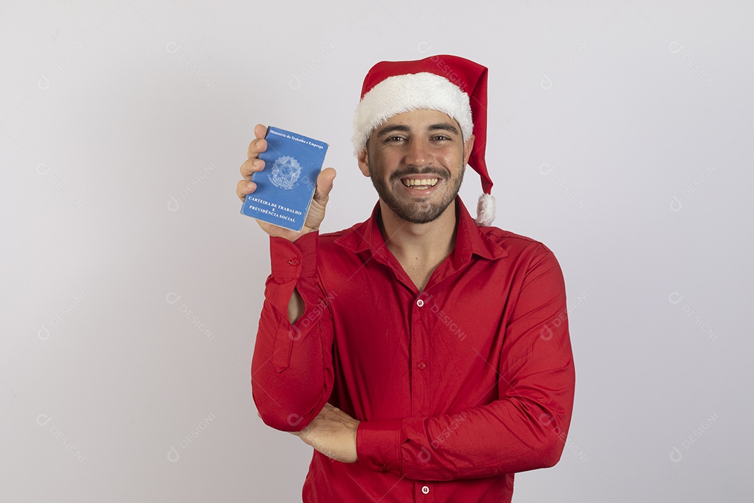 Homem jovem usando gorro Papai Noel segurando carteira de trabalho sobre fundo branco