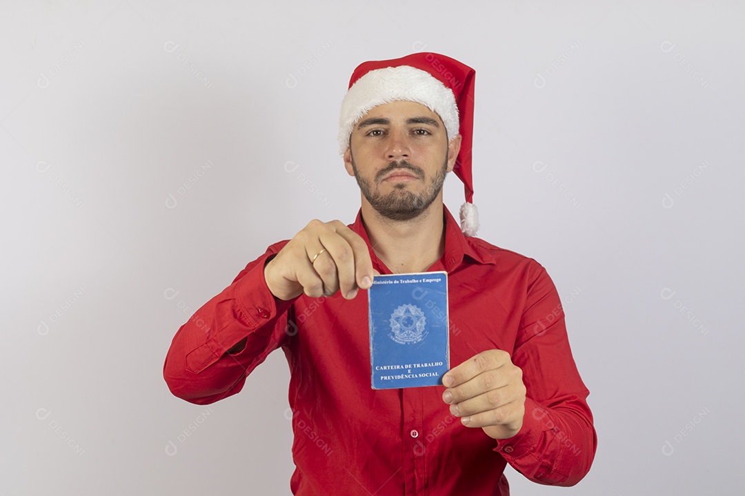 Homem jovem usando gorro Papai Noel segurando carteira de trabalho sobre fundo branco