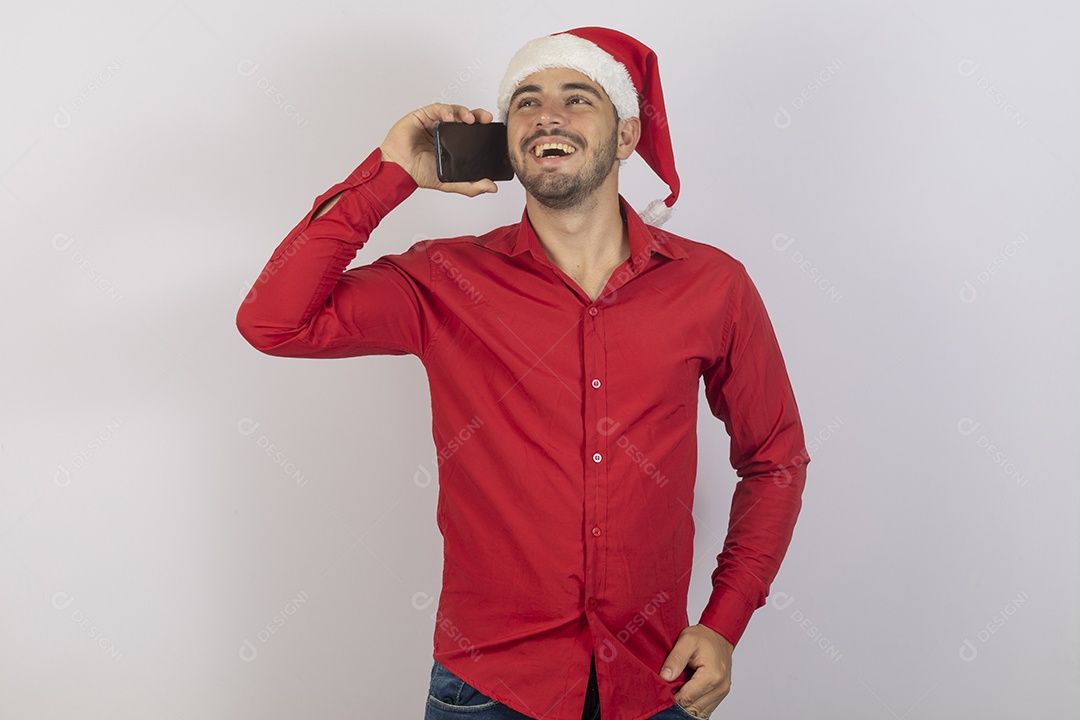 Homem jovem usando gorro Papai Noel segurando celular sobre fundo branco
