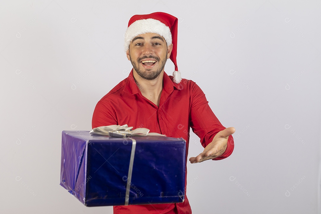 Homem jovem usando gorro Papai Noel segurando caixa de presente sobre fundo branco