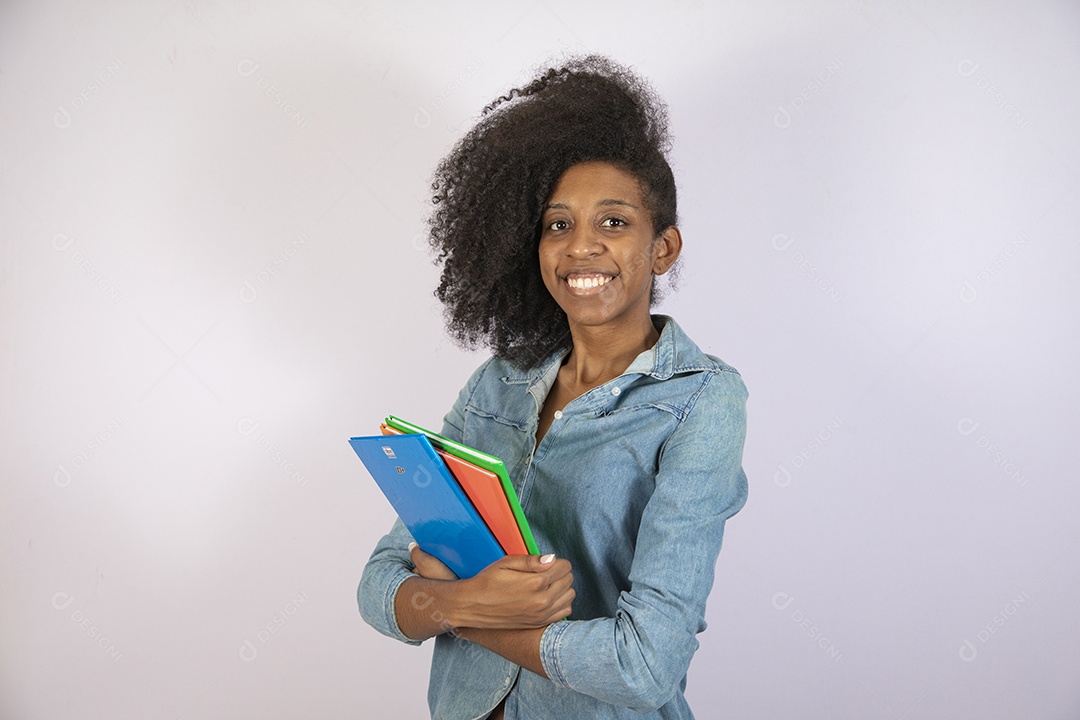 Mulher jovem negra cabelo cacheado segurando materiais escolar sobre fundo isolado branco