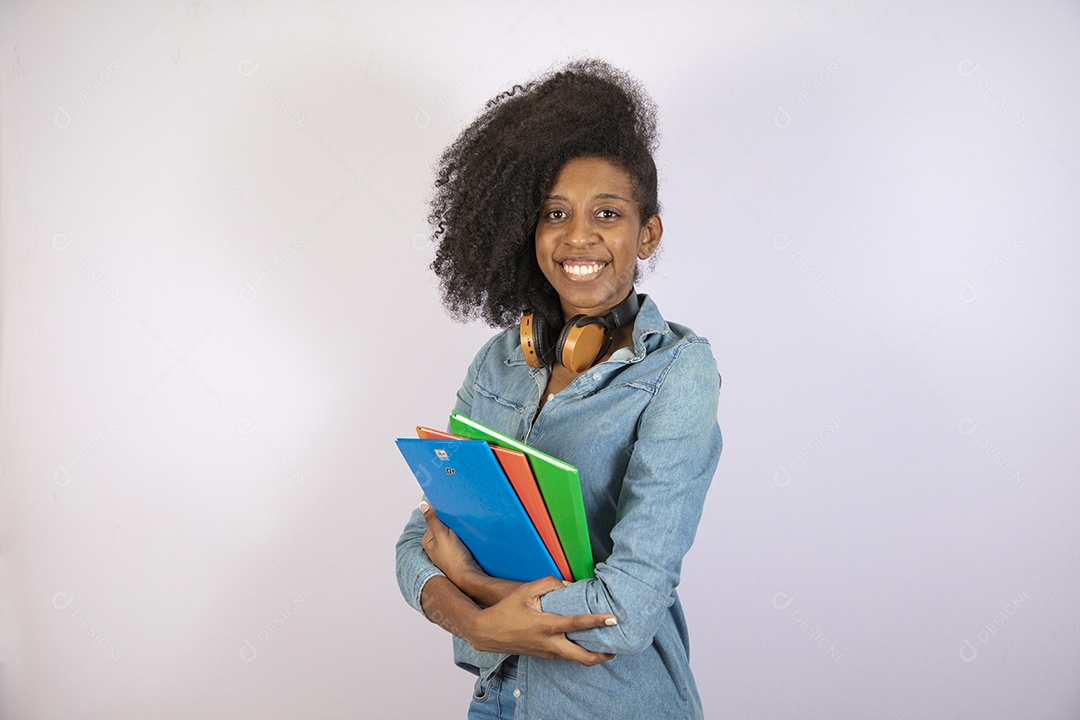 Mulher jovem negra cabelo cacheado segurando materiais escolar sobre fundo isolado branco
