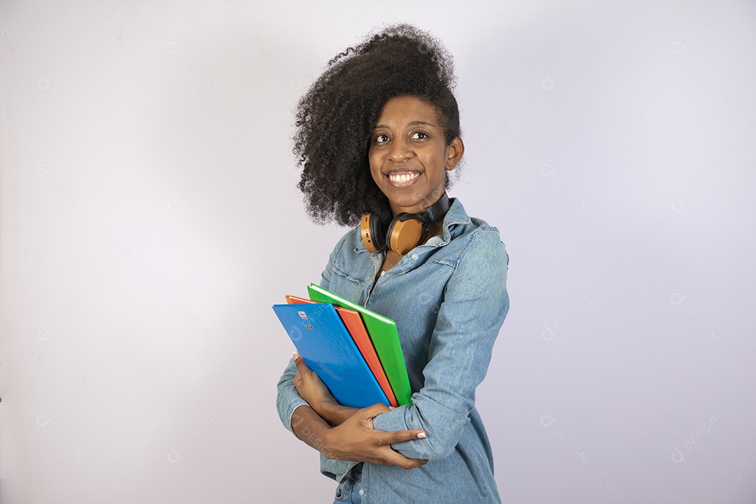 Mulher jovem negra cabelo cacheado segurando materiais escolar sobre fundo isolado branco