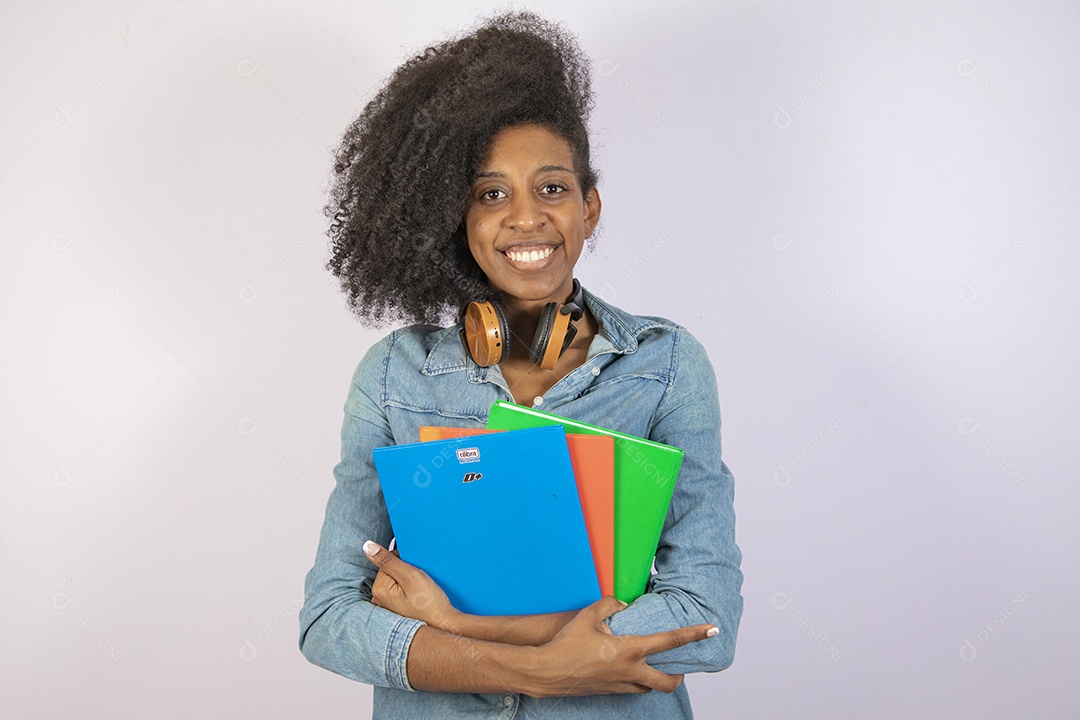 Mulher jovem negra cabelo cacheado segurando materiais escolar sobre fundo isolado branco