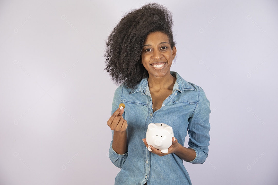 Mulher jovem negra cabelo cacheado segurando cofrinho sobre fundo isolado branco