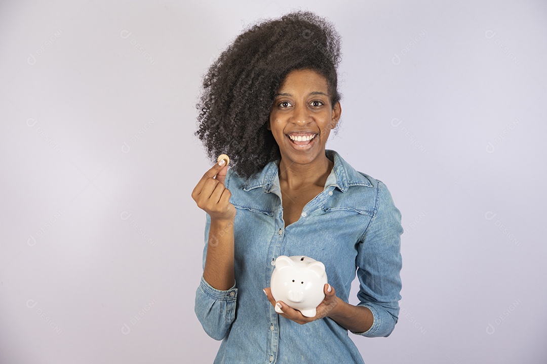 Mulher jovem negra cabelo cacheado segurando cofrinho sobre fundo isolado branco