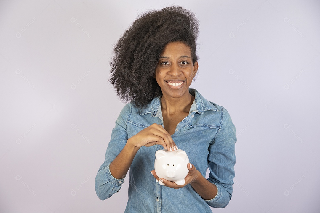 Mulher jovem negra cabelo cacheado segurando cofrinho sobre fundo isolado branco