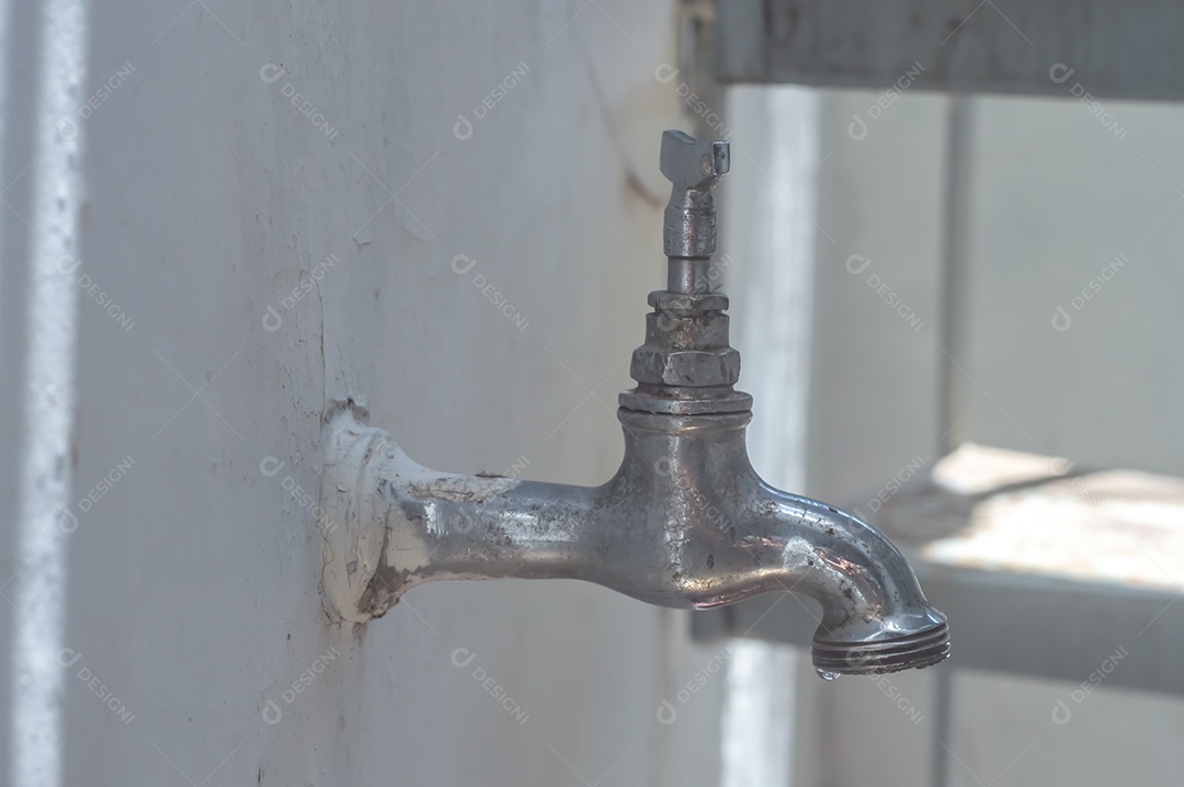 Torneira Vintage antiga e usada com gota de água, luz natural.