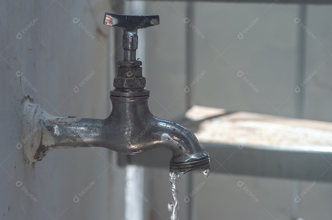 Torneira Vintage antiga e usada com gota de água, luz natural.