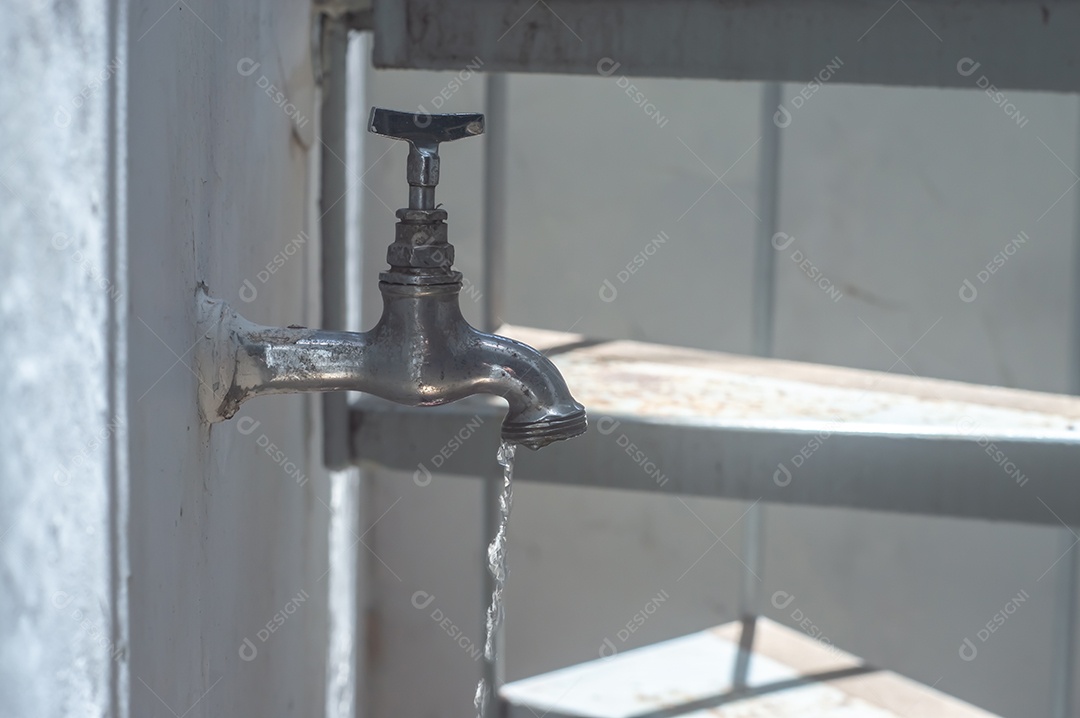 Torneira Vintage antiga e usada com gota de água, luz natural.