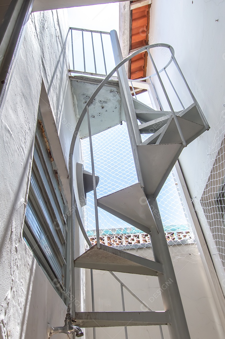 Escada circular vista de baixo para cima, vista para o céu.