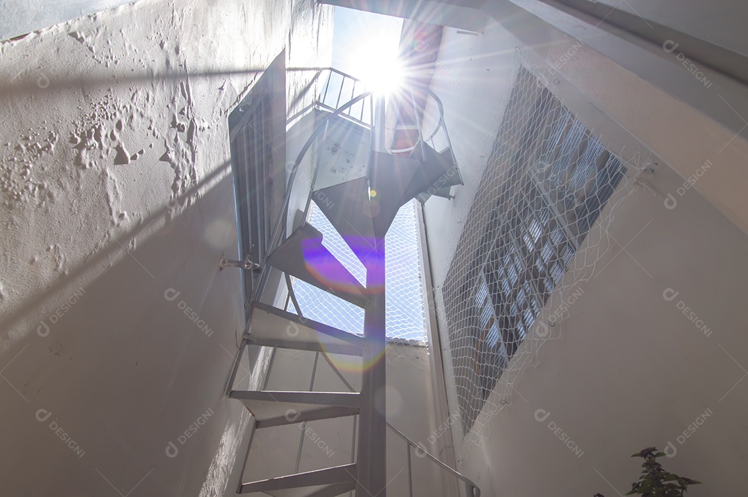 Escada circular vista de baixo para cima, vista para o céu.