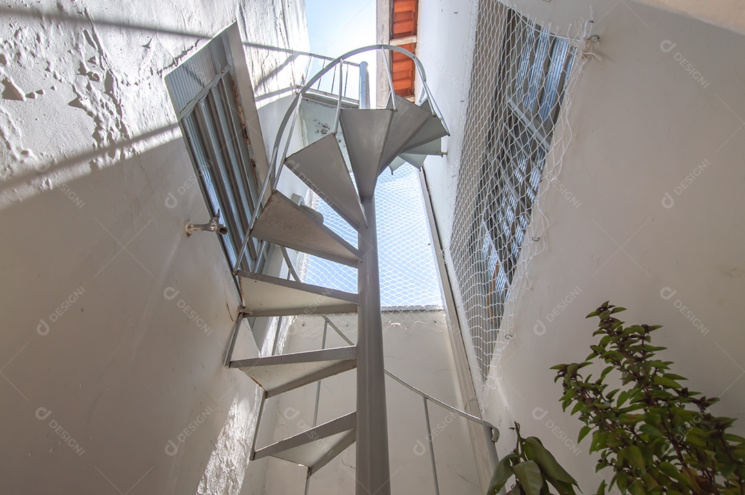 Escada circular vista de baixo para cima, vista para o céu.