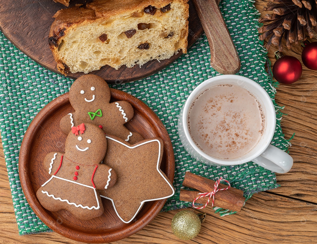 Biscoitos tradicionais de gengibre de natal e panetone sobre uma mesa de madeira.