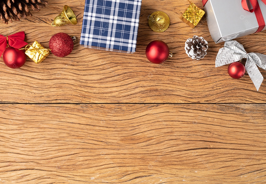 Caixas de presente, bolas de natal, sino, pinha e arco sobre madeira