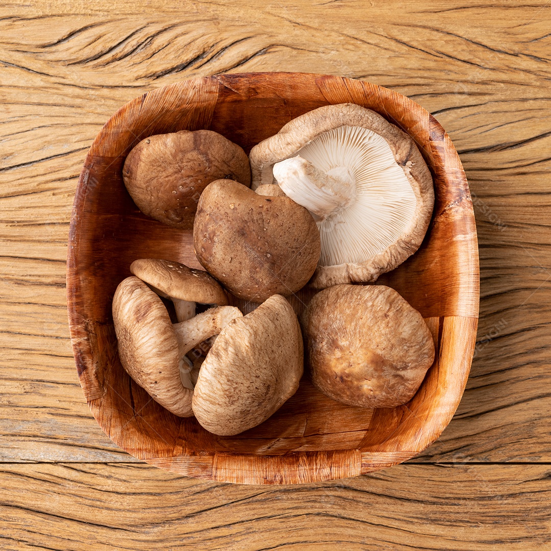 Cogumelos Shitake em uma tigela sobre a mesa de madeira.