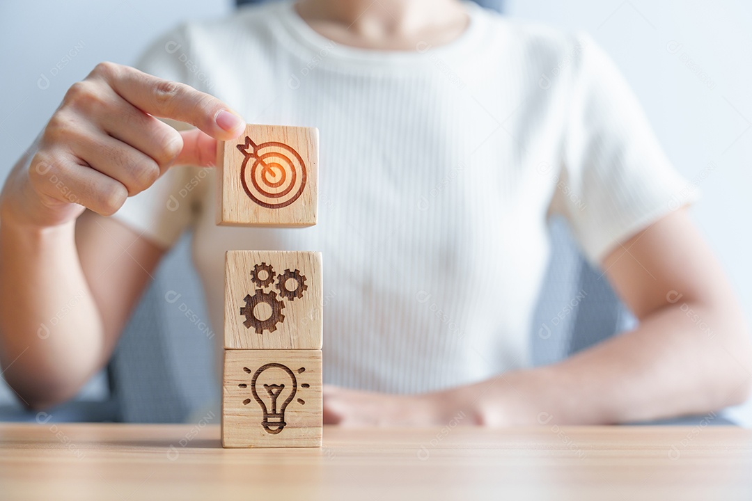 Mão de uma mulher segurando o alvo de dardos acima do bloco de ícone de engrenagem e lâmpada