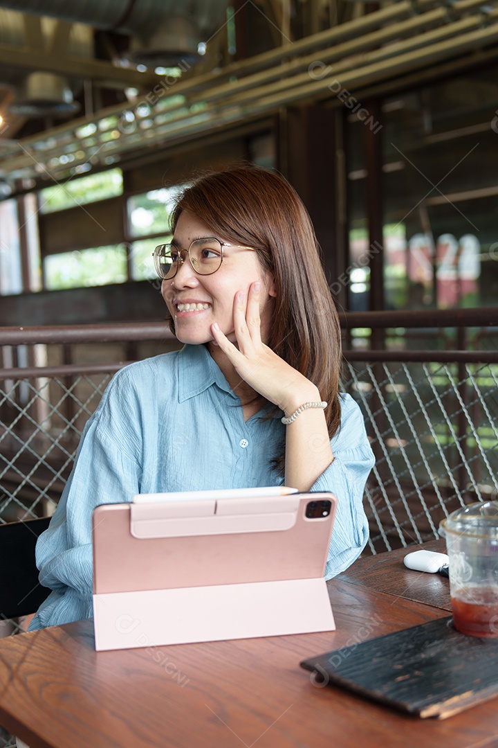Mulher asiática feliz usando tablet de computador no café