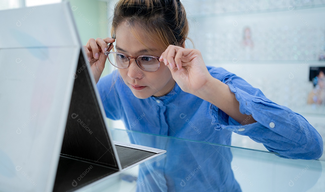 A garota experimentou os óculos e se olhou no espelho.